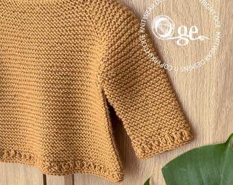 May include: A mustard yellow long-sleeved sweater featuring a garter stitch texture throughout. The garment has a round neckline and a decorative textured border along the hem and sleeve cuffs. A circular logo with the text Oge Knitwear Designs.