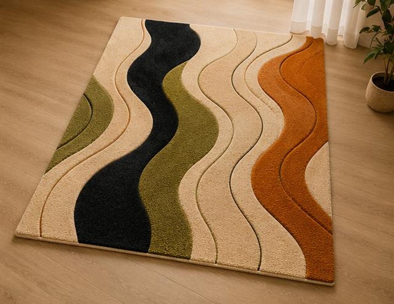 May include: A rectangular area rug featuring a textured, wavy pattern with alternating bands of cream, olive green, black, and burnt orange. The design consists of raised, curved sections that create a sense of depth across the surface of the rug.