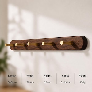 May include: A wall-mounted coat rack featuring a dark brown wooden base with five gold-toned metal hooks. The rack measures 500mm in length, 50mm in width, and 62mm in height, with a total weight of 330g. The design includes rounded edges.
