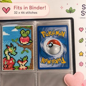 Puede incluir: Una carpeta negra que contiene un patrón de punto de cruz de un dragón verde y manzanas rojas junto a una carta coleccionable Pokemon. El texto dice Fits in Binder! 32 x 46 stitches, Shiny Stitch, Perfect binder size, Original Pokemon inspired design, Instant download, For all skill levels.