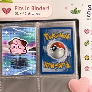 May include: A black binder containing a cross stitch pattern of a pink character on a blue background next to a standard trading card. The text reads Shiny Stitch, Fits in Binder! 32 x 46 stitches, Perfect binder size, Original Pokémon inspired design, Instant download, For all skill levels.