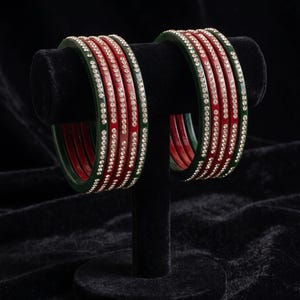 May include: A set of eight circular bangles arranged in two groups of four. Each bangle features a smooth, alternating color pattern of deep forest green and vibrant red, accented with a single row of small, clear, reflective rhinestones.