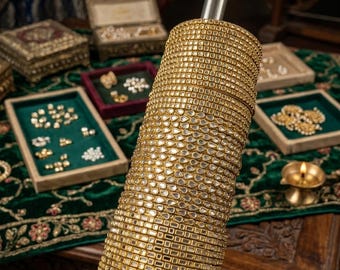 May include: A vertical stack of gold-toned bangles arranged on a cylindrical rod. The bangles feature alternating designs, including rows of small square-cut stones and rows of teardrop-shaped stones, all set in a metallic gold-colored frame.