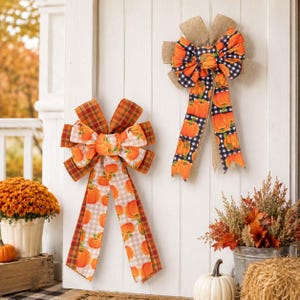May include: Two decorative bows featuring orange pumpkin patterns. The left bow has a plaid and gingham ribbon design in orange and brown. The right bow features a black and white buffalo check pattern with a burlap center accent.