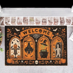 May include: A rectangular Halloween-themed doormat with a black and orange design. It features the word WELCOME in a banner above four arched panels containing illustrations of a scarecrow, a bat, a witch's cauldron, and a mummy with a lantern.