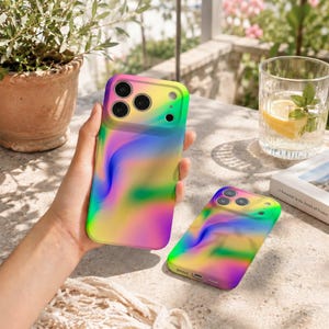 Op de afbeelding: Twee smartphonehoesjes met een levendig, meerkleurig verloopontwerp met wervelende patronen van geel, groen, blauw en paars. De hoesjes hebben een gladde afwerking en bevatten nauwkeurige uitsparingen voor de cameralenzen en flitser aan de achterkant.