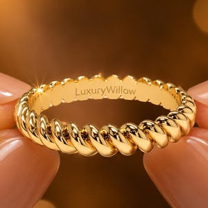 以下が含まれることがあります： バンドに沿って連続したツイストロープのテクスチャが施された、光沢のあるゴールドのリング。リングの内側にはLuxuryWillowという文字がサンセリフ体で刻印されており、明るいメタリックな仕上がりとなっています。