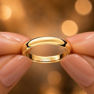 Könnte beinhalten: Ein polierter Goldring mit einer glatten, abgerundeten Oberfläche. Auf der Innenseite des Rings befindet sich der eingravierte Schriftzug LuxuryWillow in einer klaren, dunklen Schrift, was ein schlichtes und klassisches Design für Schmuckkollektionen darstellt.