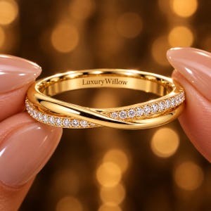 Pode incluir: Um anel de ouro com um design cruzado, em que uma banda é cravejada com pequenas pedras claras e a outra banda apresenta um acabamento liso e polido. O interior da banda tem gravado o texto LuxuryWillow numa fonte serifada escura.