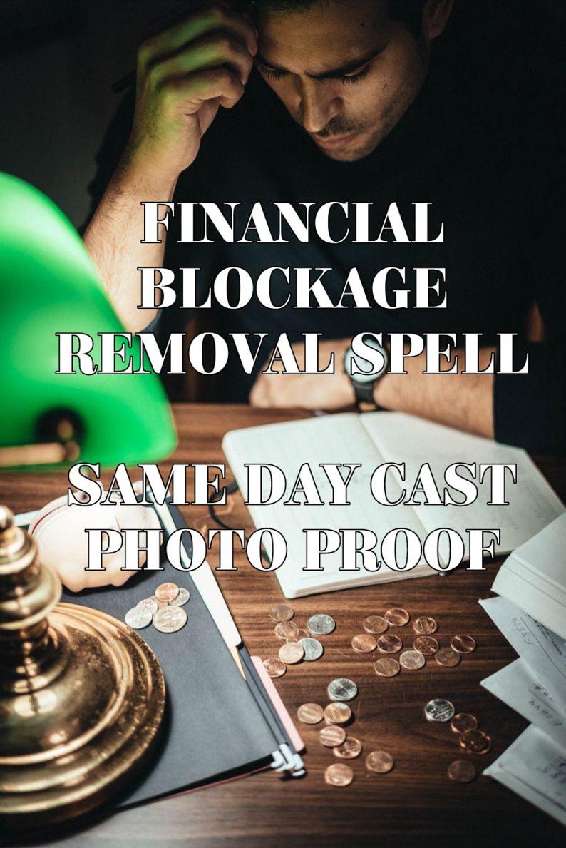 Op de afbeelding: Een persoon zit aan een houten bureau met verspreide koperkleurige munten, een notitieboek en een koperen lamp. De tekst luidt: FINANCIAL BLOCKAGE REMOVAL SPELL SAME DAY CAST PHOTO PROOF. De sc&egrave;ne is donker met een groene lampenkap links.