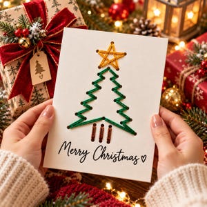 Può includere: Un biglietto d'auguri bianco con un disegno di albero di Natale ricamato a mano con filo verde, una stella gialla in cima e un tronco in filo marrone. Il testo Merry Christmas con un piccolo simbolo a cuore è stampato in nero sotto.