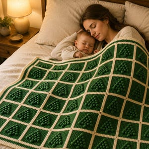 May include: A square crochet blanket featuring a grid pattern of dark green squares separated by cream-colored borders. Each green square contains a raised, textured bobble stitch design in the shape of a triangle resembling a pine tree.