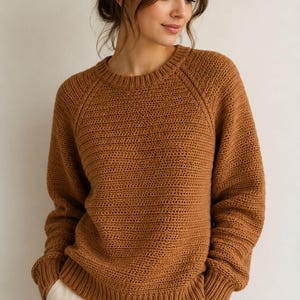 Peut inclure: Un pull à manches longues et col rond d'une couleur marron chaud unie. Le vêtement présente un motif en maille texturée sur tout le corps et les manches, avec des finitions côtelées au niveau du col, des poignets et de l'ourlet inférieur.