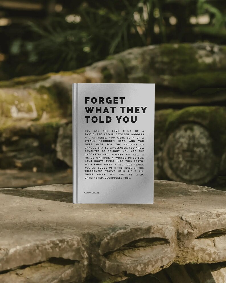 May include: A hardcover book with the title "FORGET WHAT THEY TOLD YOU" in bold black letters. The book is white and features black text on the cover and inside. The book is resting on a stone surface.