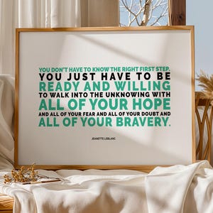 May include: A framed print with a wooden frame displays a quote in black and teal text: "YOU DON'T HAVE TO KNOW THE RIGHT FIRST STEP. YOU JUST HAVE TO BE READY AND WILLING..." The quote is attributed to Jeanette LeBlanc. The print rests on a white cloth.