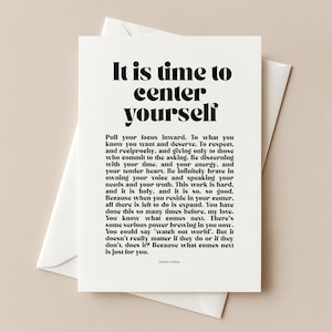 May include: A white greeting card with the text "It is time to center yourself" in a bold, black font. The card is inside a white envelope. The card also contains additional text in a smaller font.