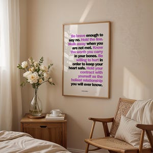Purple and black boundary print in a light wood frame hanging above a wood nightstand with a glass vase of white roses, a white teacup, and a book, beside a woven rattan chair with a cream pillow and throw. Soft light comes through sheer curtains onto a bed with cream linen. A calm bedroom setting for a self trust print, a daily reminder written by Jeanette LeBlanc to keep your own promises.