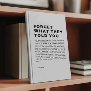 May include: A white book titled "FORGET WHAT THEY TOLD YOU" with black text. The book is on a wooden shelf with other books and decorative items. The book's text includes inspirational phrases and the author's name, Jeanette LeBlanc.