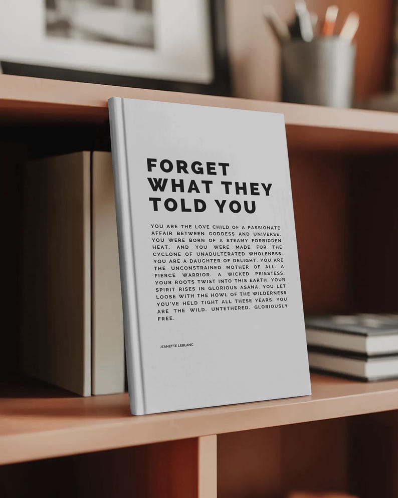 May include: A white book titled "FORGET WHAT THEY TOLD YOU" with black text. The book is on a wooden shelf with other books and decorative items. The book's text includes inspirational phrases and the author's name, Jeanette LeBlanc.