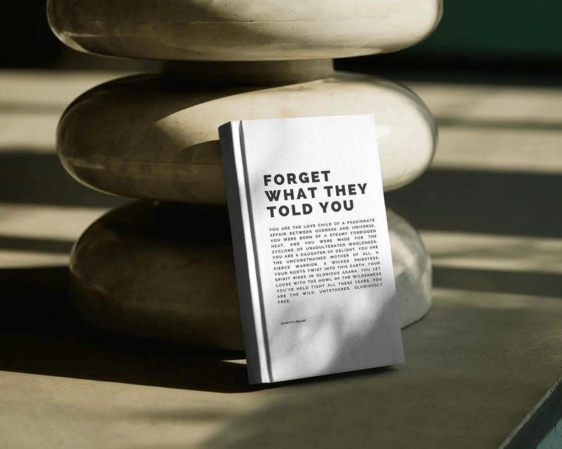 May include: A white book with the text "FORGET WHAT THEY TOLD YOU" in bold black letters. The book is propped up against a stack of three off-white, rounded, stacked objects. The book's text continues with inspirational prose.