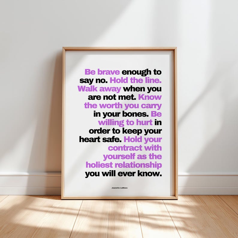 Purple and black boundary print in a light wood frame leaning against a plain white wall on a pale wood floor, with soft window light and leaf shadows across the floor. Every line is easy to read here, from Be brave enough to say no down to you will ever know, signed Jeanette LeBlanc. A bold typography print for a minimalist room, printable at home or at a print shop in the size you need.