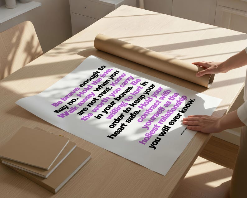 Two hands unroll a large printed copy of this boundary poster on a pale wood desk next to a roll of brown kraft paper and a stack of tan notebooks, in bright window light. The bold black and purple sans serif text runs sideways across white paper. Shows the digital file printed at poster size. A boundaries print to hang where you practice saying no, at home, in a therapist office, or at work.