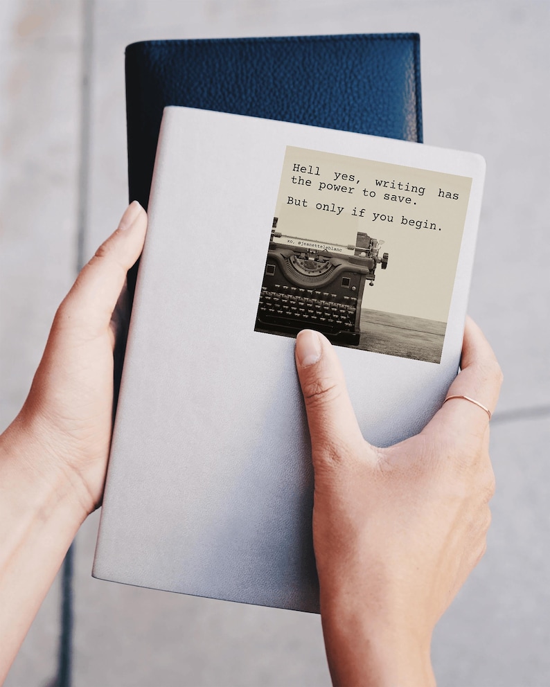 ray journal with a sticker reading “Hell yes, writing has the power to save. But only if you begin.” Featuring a vintage typewriter, this Jeanette LeBlanc quote inspires writers with storytelling encouragement and motivation.