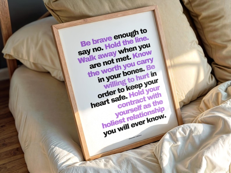 Purple and black boundary print in a light wood frame resting at an angle on rumpled cream bedding against soft beige pillows, in warm morning light. The full text by Jeanette LeBlanc is easy to read, ending with Hold your contract with yourself as the holiest relationship you will ever know. A bedroom wall art reminder for someone going through a divorce, to read first thing each day.