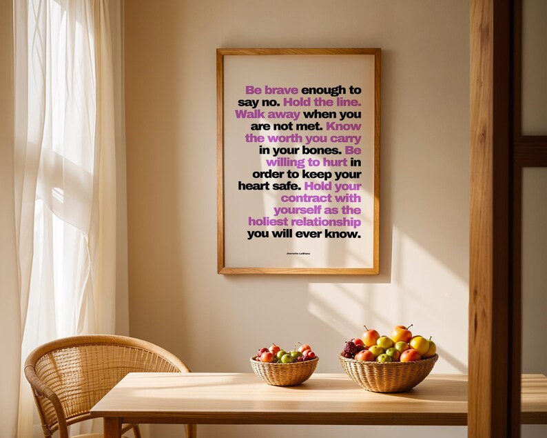 Purple and black boundary print in a light wood frame hanging on a warm beige wall above a light wood dining table with two woven baskets of apples and fruit, a rattan chair, and a sunlit sheer curtain. The purple line Walk away when you are not met reads clearly from across the room. A dining room or kitchen spot for a printable quote that the whole household sees each day.