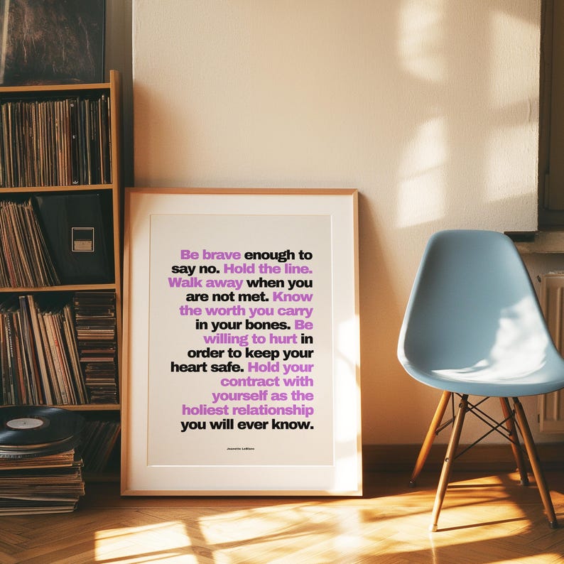 Purple and black boundary print in a light wood frame with a wide white mat leaning on a herringbone floor beside a pale blue molded chair with wood legs and a tall shelf of vinyl records. Warm late sun and window shadows stretch across the floor. A mid century look for a music lover, and a resilience print for a friend who is learning to walk away when she is not met.