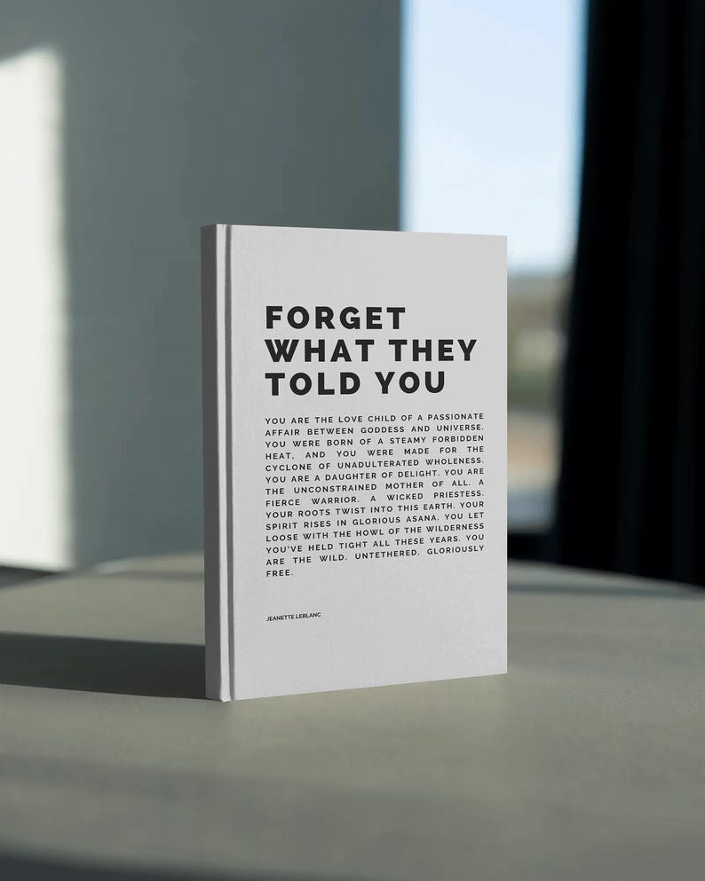 May include: A white book with the title "FORGET WHAT THEY TOLD YOU" in bold black letters. The book's pages contain inspirational text. The book is standing upright on a light-colored surface.