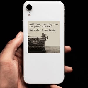 Pu&ograve; includere: Uno smartphone bianco con un'immagine in bianco e nero di una macchina da scrivere vintage sullo schermo. L'immagine contiene il testo "Hell yes, writing has the power to save. But only if you begin."