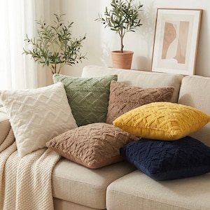 Peut inclure: Un ensemble de six coussins carrés présentant un motif géométrique en losanges texturé et en relief. Les coussins sont proposés dans une variété de couleurs unies, notamment crème, vert sauge, marron, jaune moutarde et bleu marine foncé.