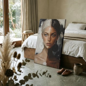 May include: A rectangular canvas print featuring a split-face portrait of a person. The left side shows light skin, blonde hair, and a blue eye, while the right side shows dark skin, dark hair, and a brown eye. Large circular earrings are visible.