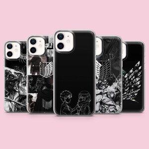 Può includere: Cinque cover trasparenti per telefono con illustrazioni in bianco e nero in stile manga tratte da L'Attacco dei Giganti. I design includono ritratti di personaggi, l'emblema alato del Corpo di Ricerca e due figure l'una di fronte all'altra.