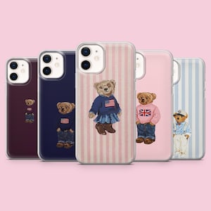以下が含まれることがあります： テディベアのイラストが描かれた5つの透明なスマートフォンケース。クマはアメリカやイギリスの国旗柄のセーター、ジーンズ、スカート、オーバーオールを着用しています。各ケースには、デュアルレンズカメラ用の切り抜きがあります。