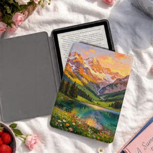 May include: An e-reader device featuring a protective cover with a printed landscape illustration of snow-capped mountains, a green valley, and a lake surrounded by colorful wildflowers. The device is open, revealing a black screen with visible text.