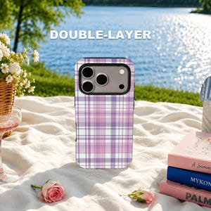 May include: A double-layer phone case featuring a purple, pink, and white plaid pattern. The case has a black camera cutout frame and is positioned upright. The text DOUBLE-LAYER is printed in white above the phone case.