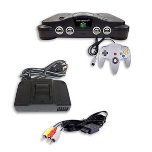 Könnte beinhalten: Eine schwarze Nintendo 64 Spielkonsole mit einem grauen Controller, einem schwarzen Netzteil mit angeschlossenem Stromkabel und einem AV-Kabel mit gelben, roten und weißen Cinch-Anschlüssen. Die Konsole zeigt das Nintendo 64 Logo auf der Vorderseite.
