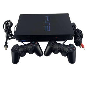 Może przedstawiać: Czarna konsola do gier Sony PlayStation 2 z logo PS2 na górnej obudowie, w zestawie z dwoma czarnymi kontrolerami Sony DualShock 2, kablem zasilającym oraz kablem AV z czerwonymi, białymi i żółtymi złączami.