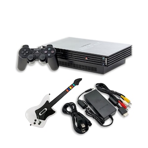 May include: A black Sony PlayStation 2 game console with a matching black controller, a white and black guitar-shaped game controller, a black AC power adapter, and a set of multi-colored AV cables with yellow, white, and red connectors.