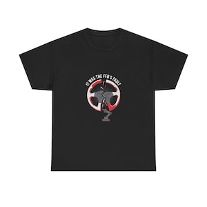 May include: A black short-sleeve t-shirt featuring a graphic of a broken red and white racing steering wheel. The text "IT WAS THE FFB'S FAULT" is printed in white above the wheel, with a small gray mechanical arm icon positioned below it.