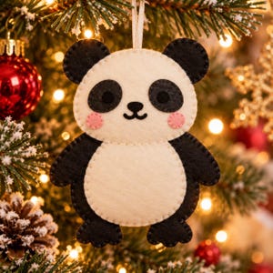 May include: A felt panda ornament featuring a cream-colored body with black ears, arms, legs, and eye patches. The panda has a small black nose, a curved mouth, and two pink circular cheeks. A white ribbon loop is attached to the top for hanging.