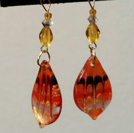 Orange glass drop earrings with wave design and gold accents.