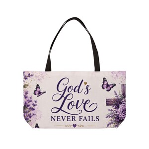Puede incluir: Un bolso tote con fondo morado claro decorado con flores de lavanda, mariposas moradas y una cruz de madera. El texto God's Love NEVER FAILS aparece en letras moradas oscuras, junto a un pequeño corazón morado y líneas doradas.