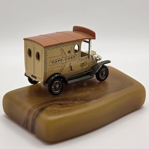 May include: A die-cast model delivery van in cream and brown with black fenders and wheels. The side features the text "Australian Days-Gone Collectors Club" with illustrations of a boomerang, a kangaroo, and an emu, plus decorative patterns.