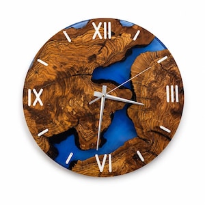 May include: A round wall clock featuring a natural wood slab with prominent grain patterns and a vibrant blue resin inlay. The clock face displays white Roman numerals at the twelve, three, six, and nine o'clock positions, with silver hands.