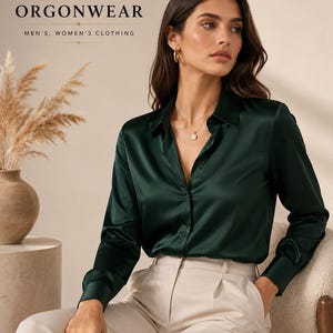 May include: A dark emerald green long-sleeve button-down shirt with a satin finish, a classic collar, and buttoned cuffs. The shirt is paired with light beige trousers. The image includes the text ORGONWEAR MEN'S, WOMEN'S CLOTHING.