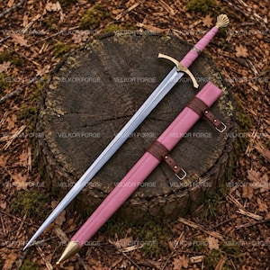 Puede incluir: Una espada larga con hoja de acero plateado, guarda dorada y empuñadura envuelta en rosa rematada con un pomo dorado. La espada incluye una vaina rosa a juego con correas de cuero marrón y una punta de metal de tono dorado.