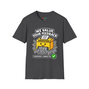 May include: A dark gray short-sleeve t-shirt featuring a graphic of a yellow paper shredder with a smiling face. The text reads WE VALUE YOUR FEEDBACK, SUGGESTIONS, and SHREDDER CONNECTED with a green checkmark icon below the shredder.